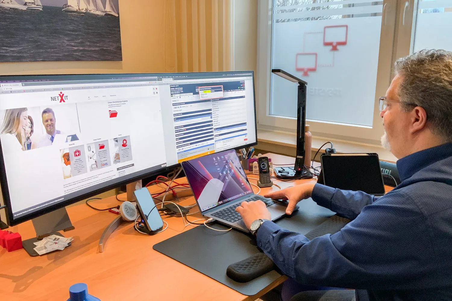 IT-Administrator arbeitet am Laptop mit Dual-Monitor, Netzwerk-Software im Büro